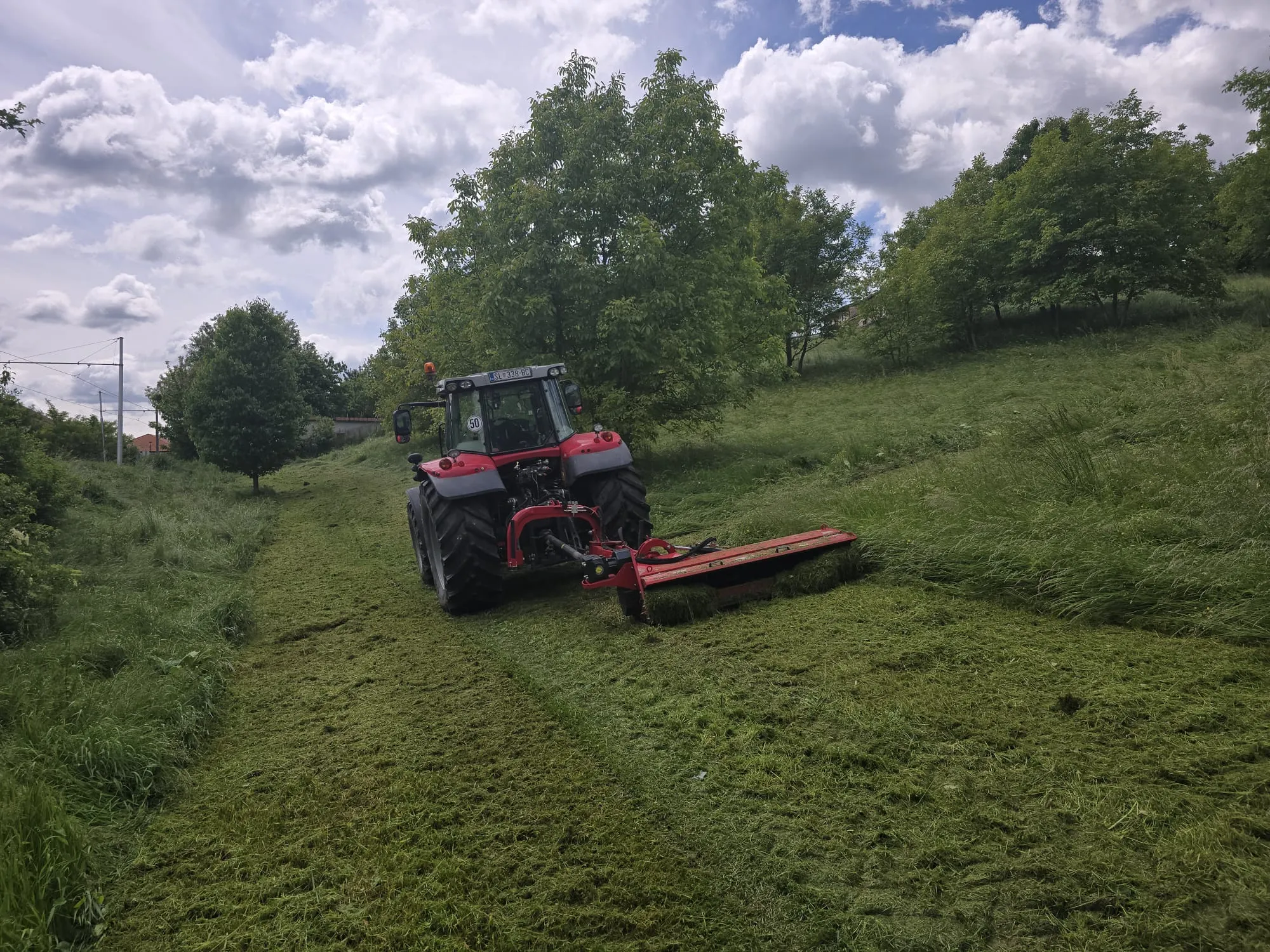 Traktor s malčerom kosi travnatu padinu
